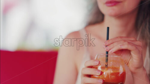 Close up of a woman sipping fresh carrot juice through a straw - Starpik Stock