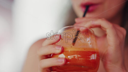 Close up of a woman sipping fresh carrot juice through a straw - Starpik Stock