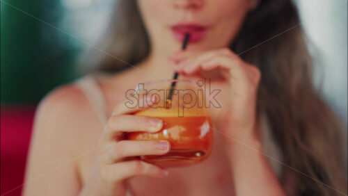 Close up of a woman sipping fresh carrot juice through a straw - Starpik Stock
