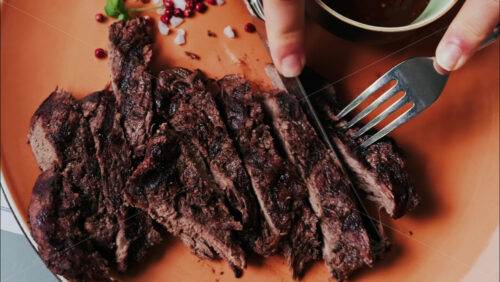 Close up of a woman’s hands cutting a Sirloin Steak with Barbecue Sauce and micro-plants on the side - Starpik Stock