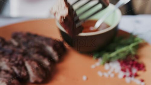 Close up of a woman’s hands cutting a Sirloin Steak with Barbecue Sauce and micro-plants on the side - Starpik Stock