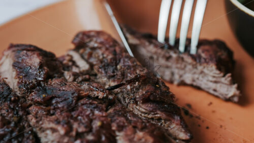 Close up of a woman’s hands cutting a Sirloin Steak with Barbecue Sauce and micro-plants on the side - Starpik Stock