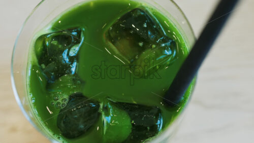 Close up of an iced matcha in a glass with a black straw at a cafe - Starpik Stock