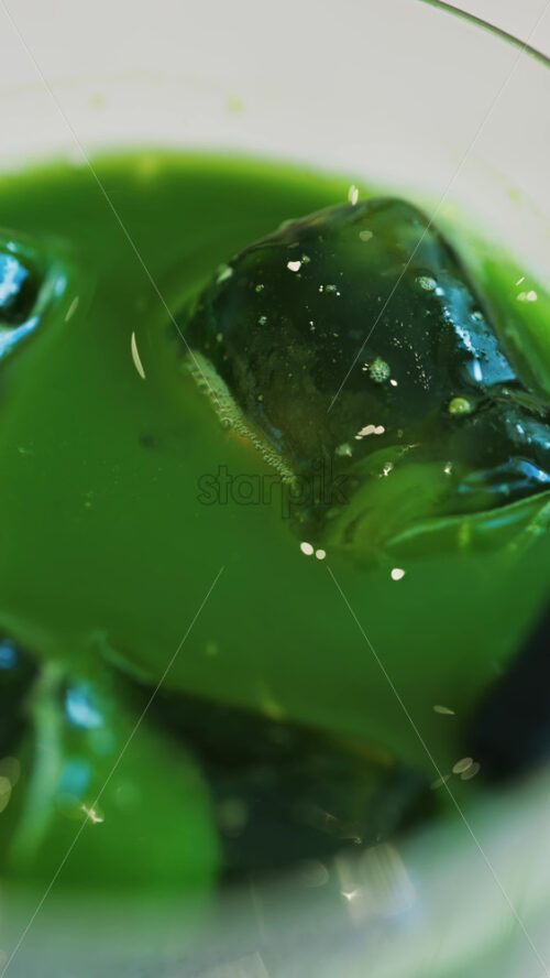 Close up of an iced matcha in a glass with a black straw at a cafe. Vertical - Starpik Stock