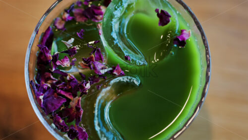 Close up of an iced matcha in a glass with purple dried flowers on top - Starpik Stock