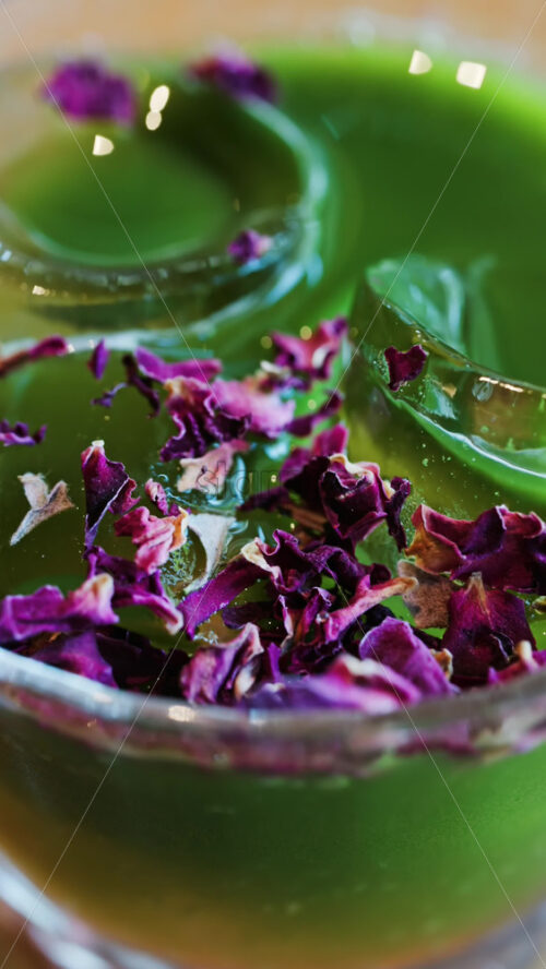 Close up of an iced matcha in a glass with purple dried flowers on top. Vertical - Starpik Stock