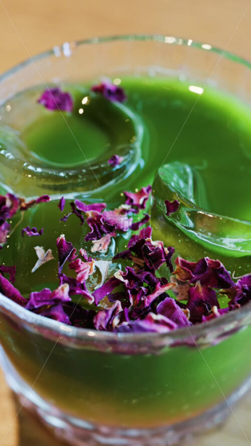 Close up of an iced matcha in a glass with purple dried flowers on top. Vertical - Starpik Stock