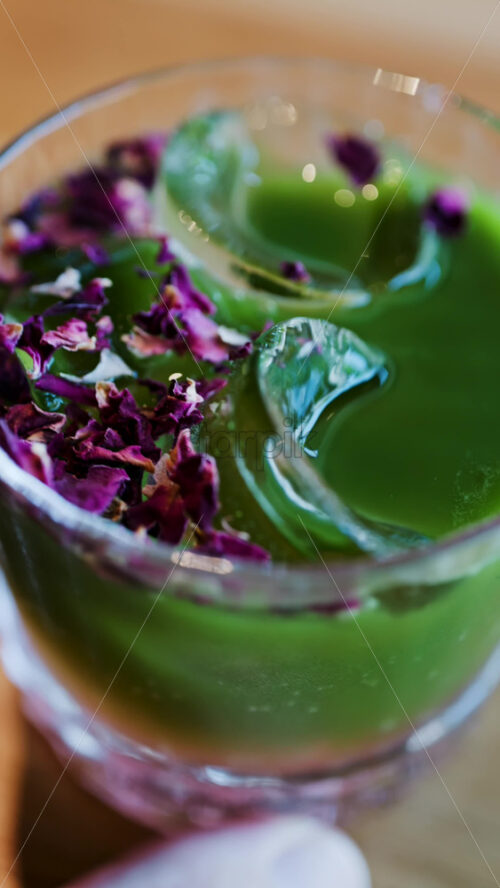 Close up of an iced matcha in a glass with purple dried flowers on top. Vertical - Starpik Stock