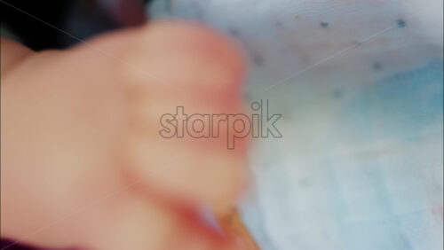 Close up of baby’s foot resting on a patterned blanket with natural light - Starpik Stock