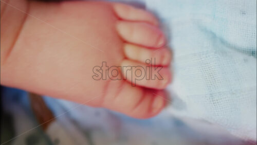 Close up of baby’s foot resting on a patterned blanket with natural light - Starpik Stock