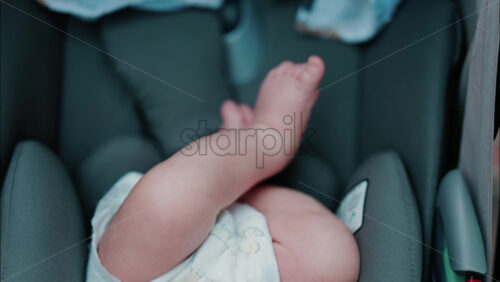 Close up of baby’s tiny feet crossed inside a protective car seat - Starpik Stock