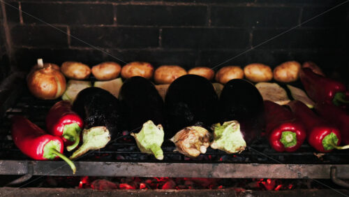 Close up of eggplants, potatoes, onions, peppers and courgettes cooking on a grill - Starpik Stock