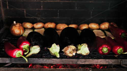 Close up of eggplants, potatoes, onions, peppers and courgettes cooking on a grill - Starpik Stock