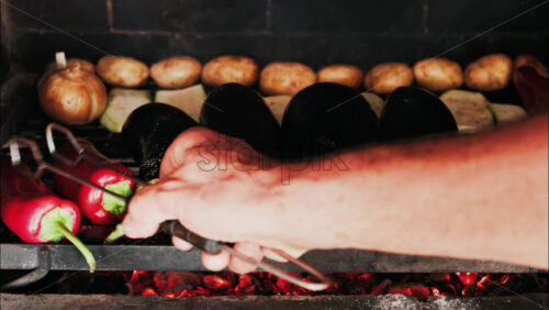 Close up of eggplants, potatoes, onions, peppers and courgettes cooking on a grill - Starpik Stock