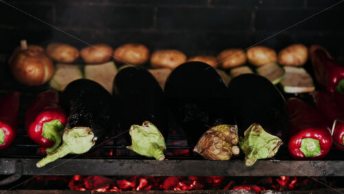 Close up of eggplants, potatoes, onions, peppers and courgettes cooking on a grill - Starpik Stock