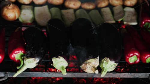 Close up of eggplants, potatoes, onions, peppers and courgettes cooking on a grill - Starpik Stock