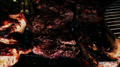 Close up of meats cooking on a grill alongside golden potatoes, asparagus, and garlic - Starpik Stock