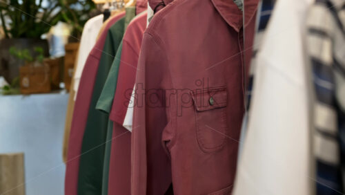 Close up of multiple clothes hanging on a rack in a hipster clothing store - Starpik Stock