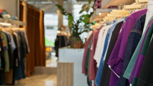 Close up of multiple clothes hanging on a rack in a hipster clothing store - Starpik Stock