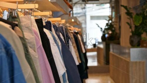 Close up of multiple clothes hanging on a rack in a hipster clothing store - Starpik Stock