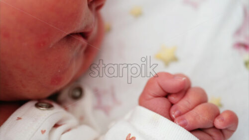Close up of newborn’s hand gently clenched near the face, capturing delicate skin texture - Starpik Stock