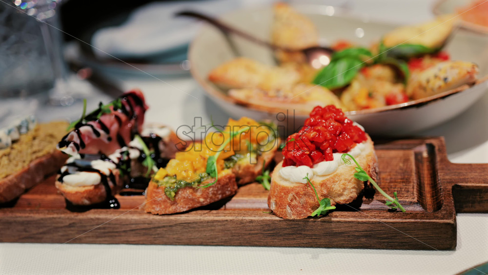 Close up of rustic bruschetta topped with cream cheese and roasted red peppers, garnished with fresh greens - Starpik Stock