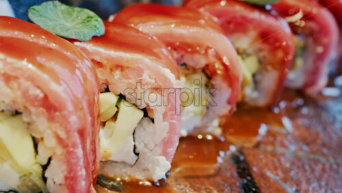 Close up of sushi with a sauce drizzle on a glass tray at a restaurant - Starpik Stock