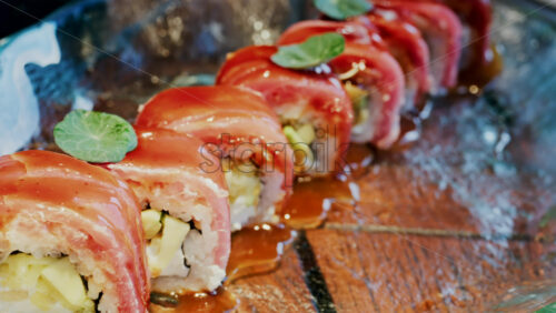 Close up of sushi with a sauce drizzle on a glass tray at a restaurant - Starpik Stock