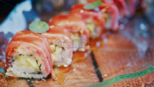 Close up of sushi with a sauce drizzle on a glass tray at a restaurant - Starpik Stock