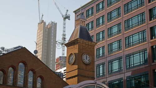 Close up of the clock tower at Liverpool Street Station with construction cranes and modern buildings in the background in London, England - Starpik Stock