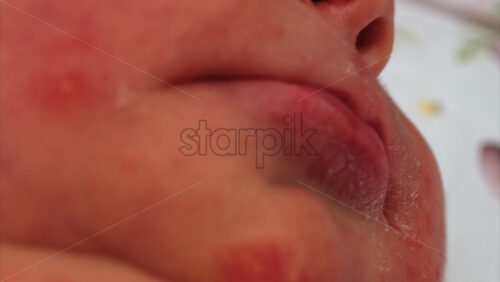 Close up of the small, red lips of a newborn baby in soft natural light - Starpik Stock