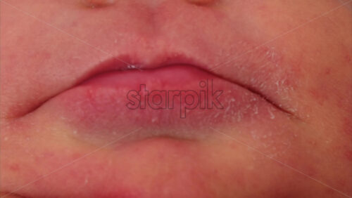 Close up of the small, red lips of a newborn baby in soft natural light - Starpik Stock