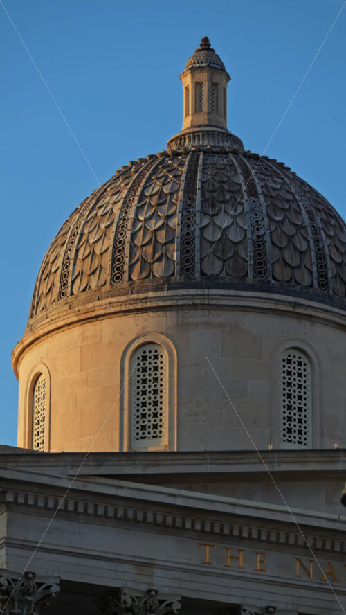 Close up of the top of The National Gallery building over blue sky. Vertical - Starpik Stock