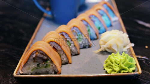 Close up of triangle shaped salmon sushi on a platter with wasabi and gari - Starpik Stock