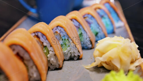 Close up of triangle shaped salmon sushi on a platter with wasabi and gari - Starpik Stock