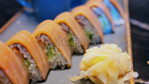 Close up of triangle shaped salmon sushi on a platter with wasabi and gari - Starpik Stock