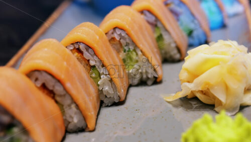 Close up of triangle shaped salmon sushi on a platter with wasabi and gari - Starpik Stock