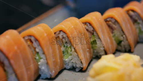 Close up of triangle shaped salmon sushi on a platter with wasabi and gari - Starpik Stock