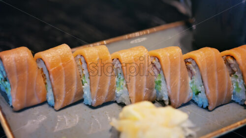 Close up of triangle shaped salmon sushi on a platter with wasabi and gari - Starpik Stock