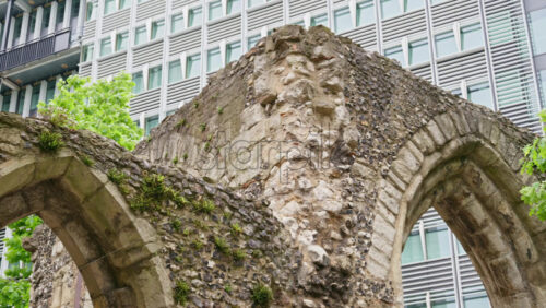 Close-up shot of ancient Roman wall ruins with modern office buildings located in the London Wall Place garden - Starpik Stock