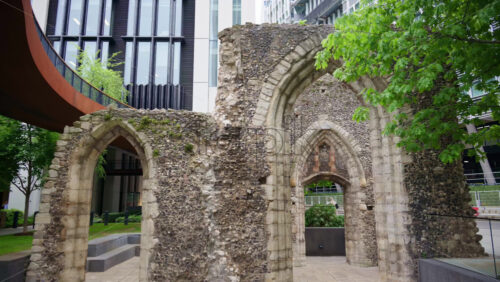 Close-up shot of ancient Roman wall ruins with modern office buildings located in the London Wall Place garden - Starpik Stock