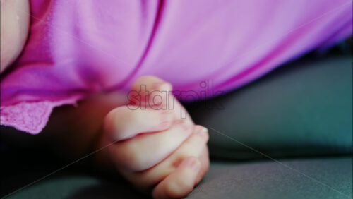 Close up view of a baby’s hand and fingers curled in a natural pose while resting - Starpik Stock