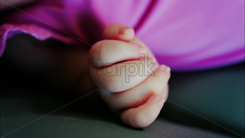 Close up view of a baby’s hand and fingers curled in a natural pose while resting - Starpik Stock