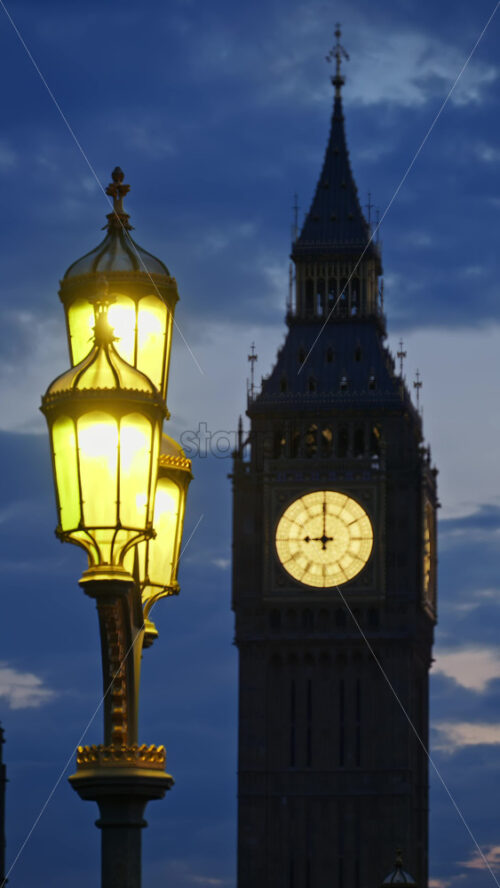 Close-up view of a street lamp illuminated in front of the Big Ben illuminated at dusk in London, England. Vertical - Starpik Stock