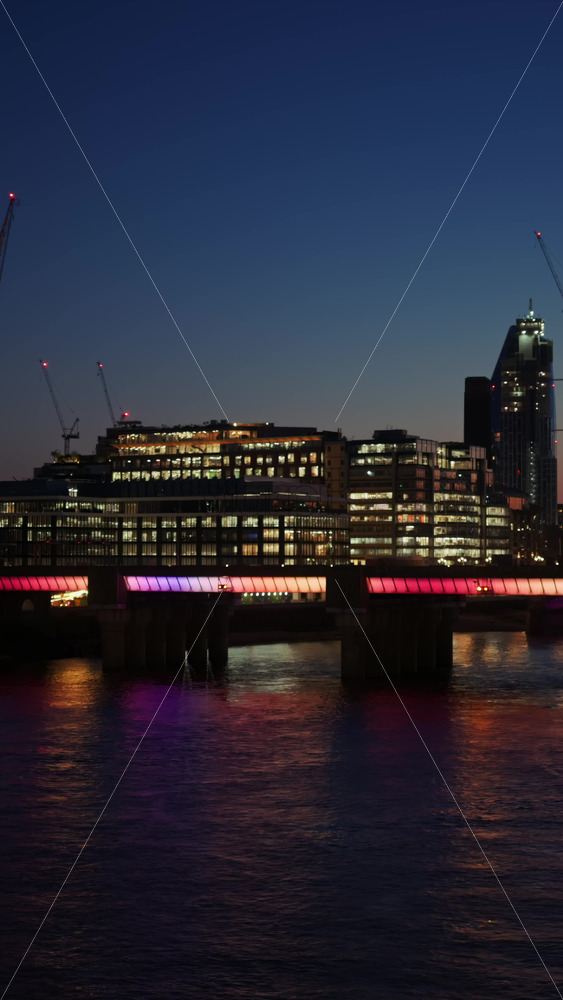 Colourful lights from Cannon Street Railway Bridge reflecting on the Thames River at twilight in London, England. Vertical - Starpik Stock