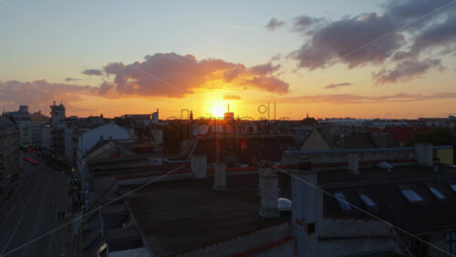 Copenhagen, Denmark – August 3, 2025: Aerial drone view of a beautiful street in the city at dusk, with colourful clouds and the sun setting behind historic buildings - Starpik Stock