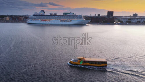 Copenhagen, Denmark – August 3, 2025: Aerial drone view of a cruise ship docked in Copenhagen harbor near Langelinie with a yellow harbor bus sailing nearby - Starpik Stock