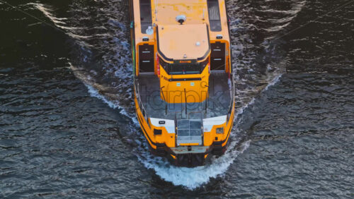 Copenhagen, Denmark – August 3, 2025: Aerial drone view of a yellow ferry boat passing under a modern bridge on the the Nyhavn canal - Starpik Stock
