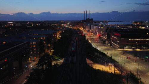 Copenhagen, Denmark – August 3, 2025: Aerial drone view of the Dybbolsbro train station with a red S-train arriving, next to Fisketorvet shopping center and Kalvebod Brygge - Starpik Stock