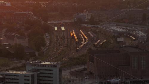 Copenhagen, Denmark – August 3, 2025: Aerial drone view of train tracks at the Copenhagen Central Station glowing at sunset - Starpik Stock